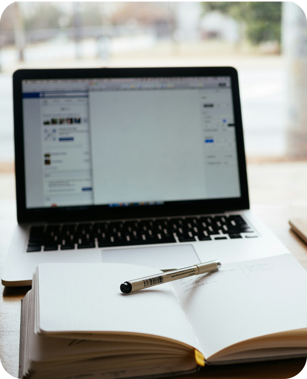 A laptop showing a course, and a book and pen